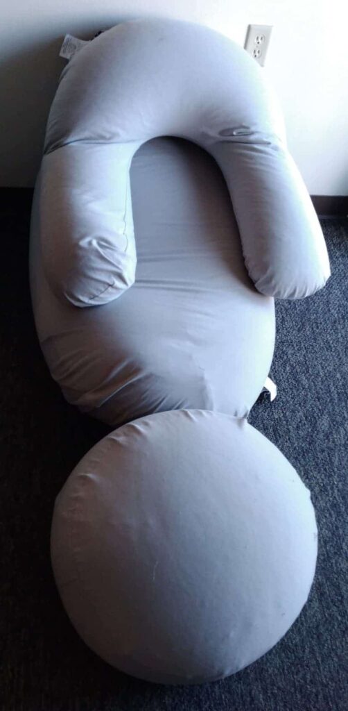 Large gray U-shaped body pillow with matching round cushion, designed for full-body support while lounging or resting.