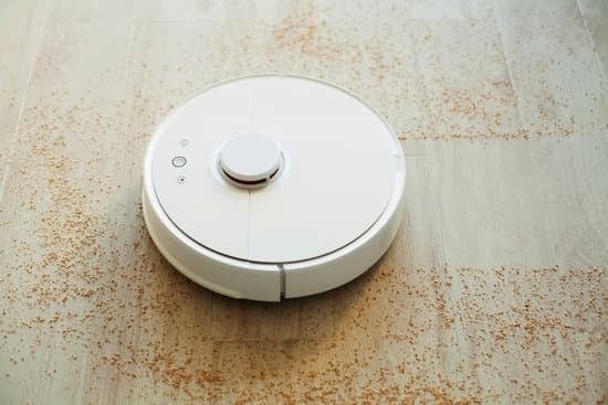Robot vacuum cleaner moving across a hard floor, picking up scattered dirt and debris.