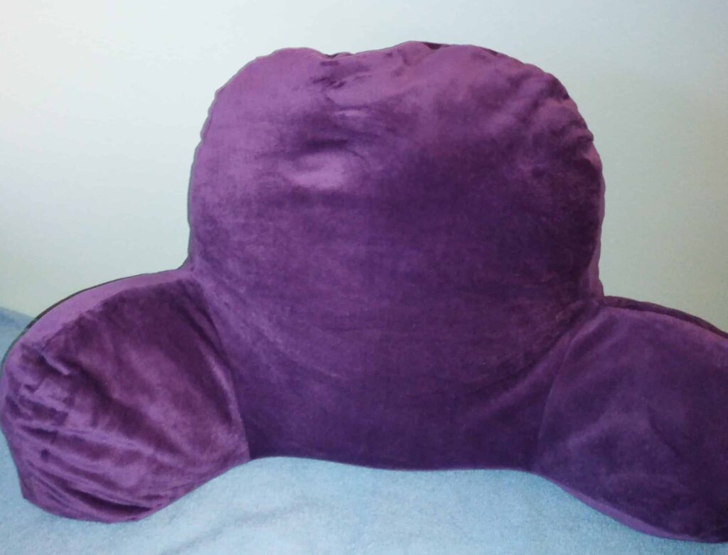 Purple backrest reading pillow with arm supports, designed for sitting up in bed or on a couch.